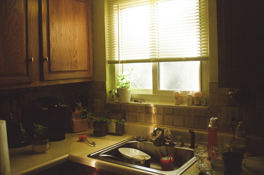 Sunlit kitchen with medication bottles on the windowsill and dishes in the sink, signs an aging parent may need help at home